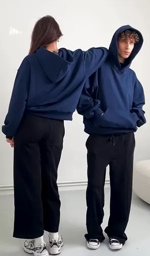 Two people wearing matching blue hoodies and black pants on a white background