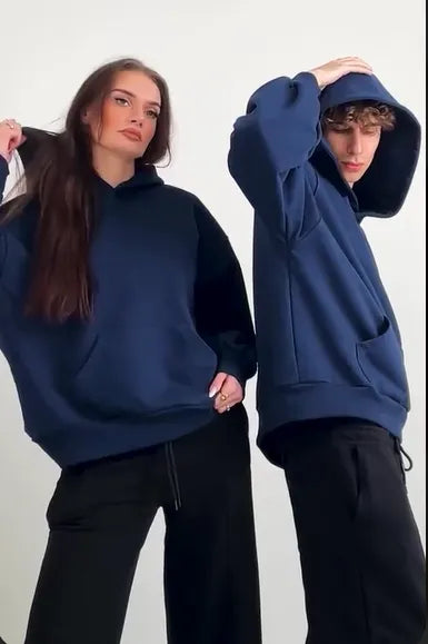 Two people wearing navy blue hoodies and black pants on a white background