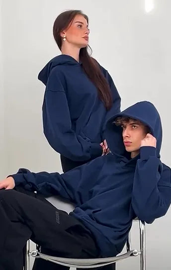 Two people wearing navy blue hoodies against a white background