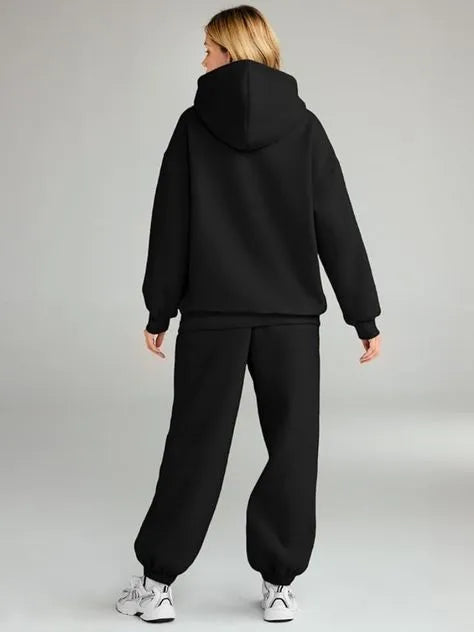 Person wearing a black hoodie and black pants on a gray background
