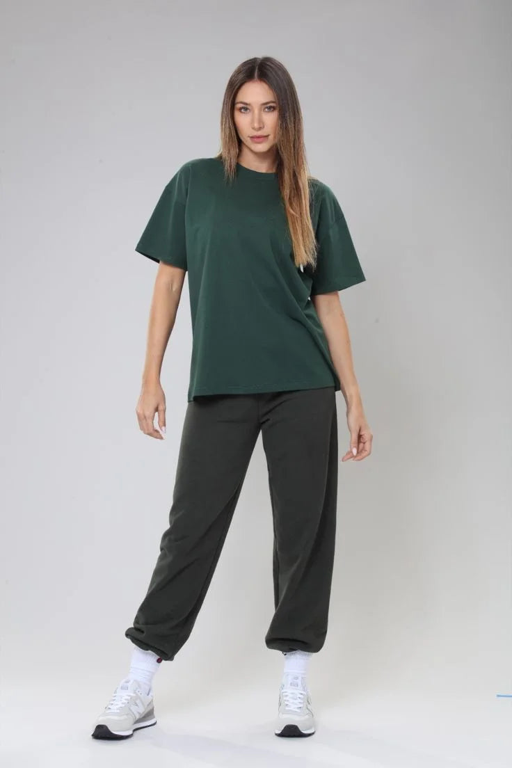 Woman wearing a green t-shirt and black pants on a gray background