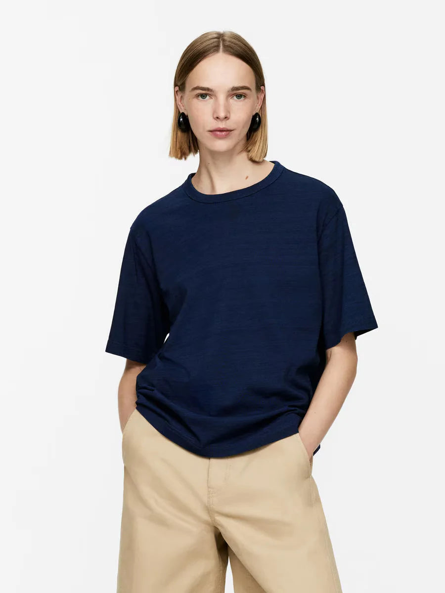 Person wearing a navy blue t-shirt and beige pants on a white background