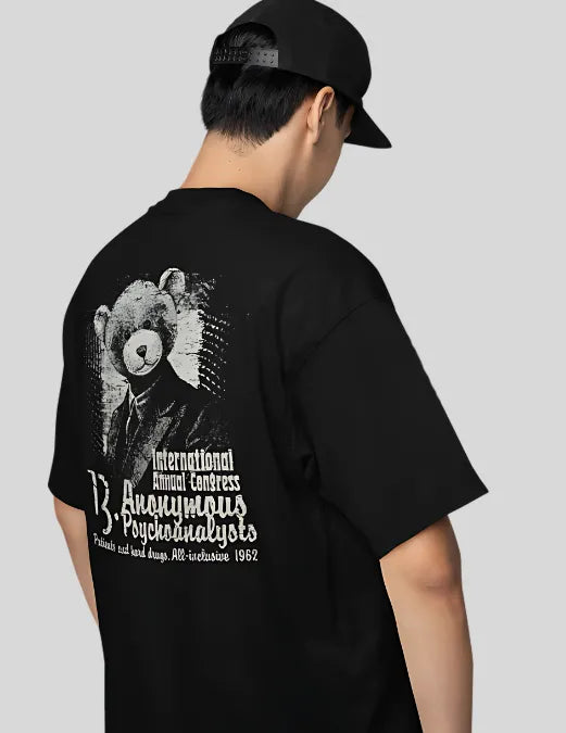 Person wearing a black t-shirt with a graphic design on the back against a plain background